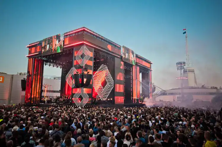 Duża scena festiwalowa z ekranami LED o zmierzchu, tłum przed sceną